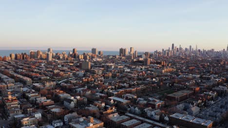 Dramatic-Aerial-View-of-Subway-Train-in-the-Distance-Traveling-North-in-Chicago-Neighborhood-with-City-Skyline-in-Background