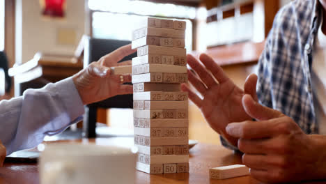 mid section of friends playing jenga 4k