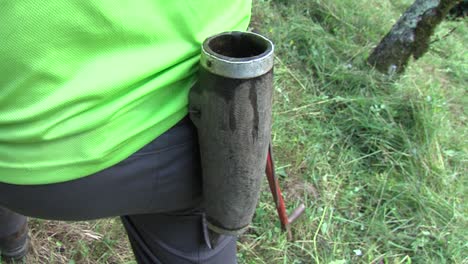 agricultor masculino con cinturón con soporte para piedra de afilar durante la siega del césped, primer plano