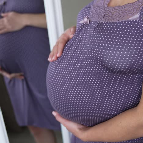 woman hands touching her tummy, waiting child. pregnant expectant mother looking at her reflection and stroking her stomach lovingly. close up shot