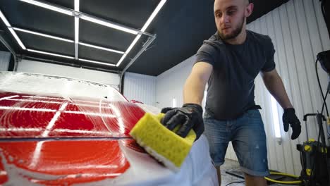 man worker washing red car on a car wash.