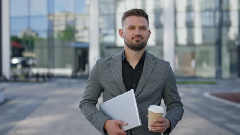 businessman walking in city with laptop and coffee