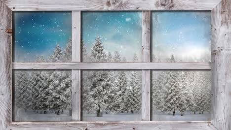 wooden window frame against snow falling over multiple trees on winter landscape