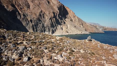 drone acercándose a un turista caminando hacia un acantilado para revelar un paisaje espectacular y una playa bajo un acantilado en el sur de creta
