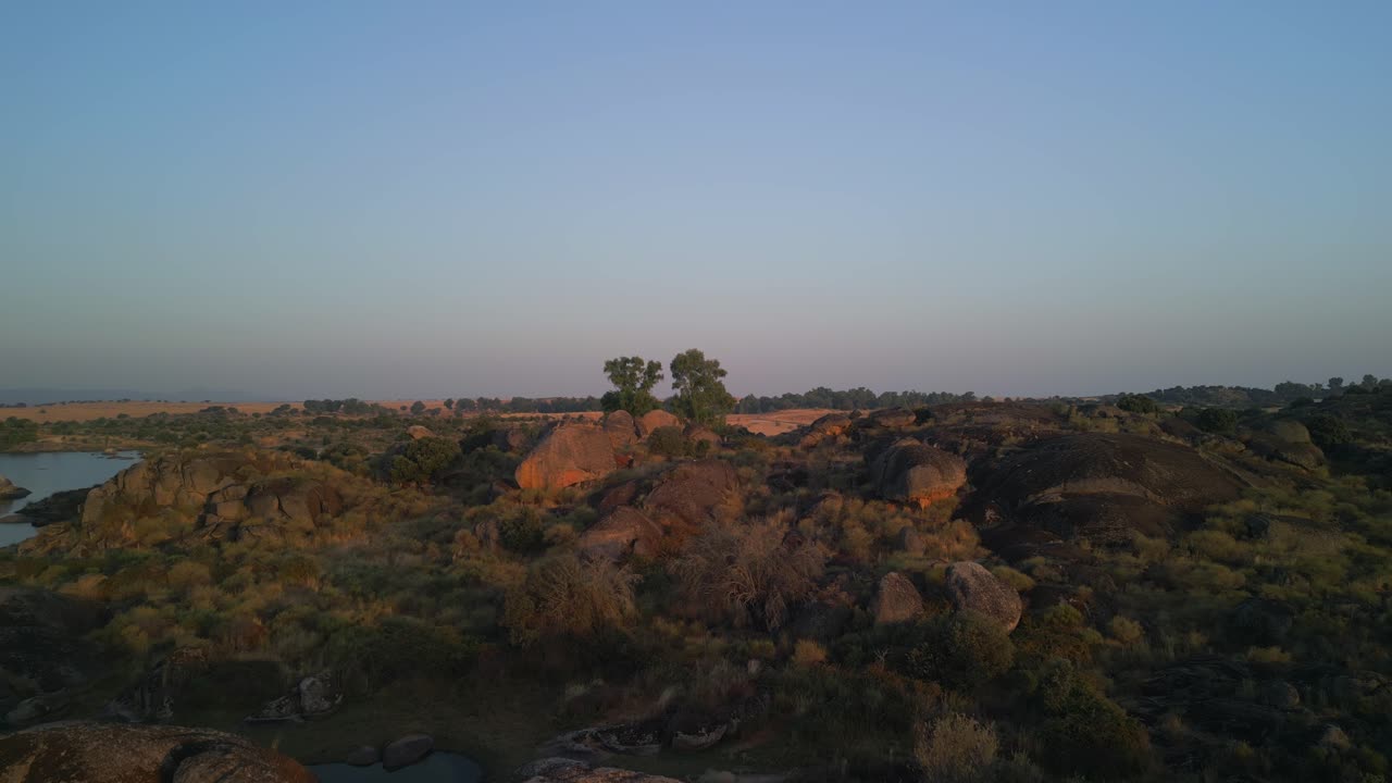 Vasta paisagem árida com rochas e lago sob céu azul
