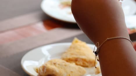 person cutting and eating an omelette at a table