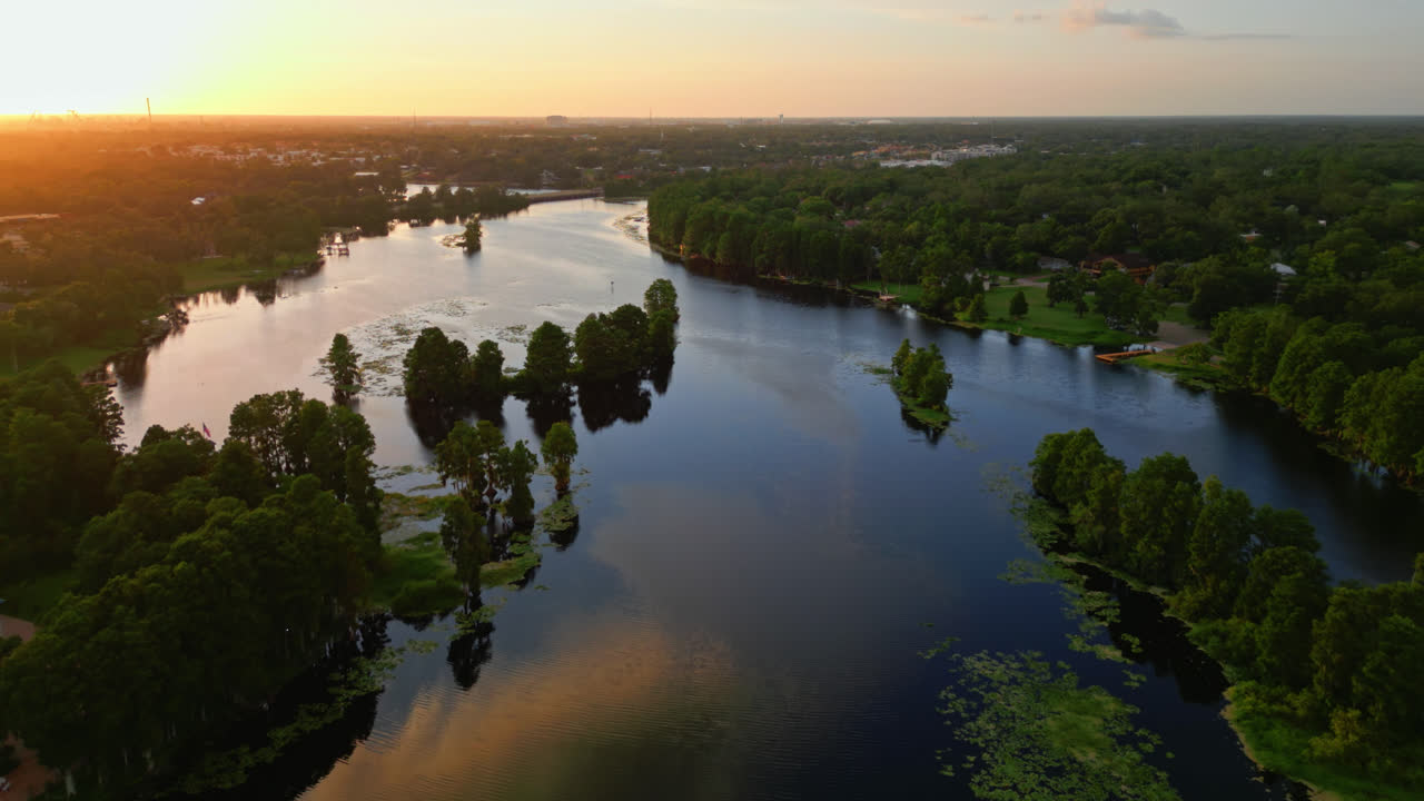 Bagliore del tramonto che si riflette sulla superficie del fiume con una proprietà sul lungofiume di lato, toni caldi in un paesaggio acquatico tranquillo, sfondo naturale, vista aerea