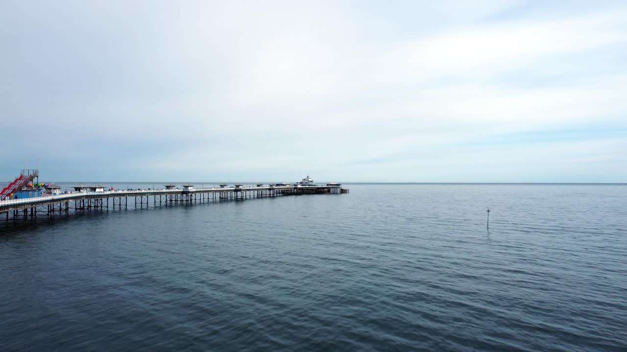 Elegante e lungo pontile vittoriano gallese di Llandudno, vista aerea a bassa quota sull'acqua in una tranquilla mattinata.
