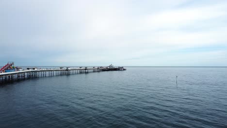 Elegante-Dehnung-Viktorianischen-Walisischen-Llandudno-Pier-Luftaufnahme-Niedrig-Zu-Wasser-An-Einem-Ruhigen-Morgen