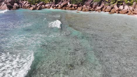 Aerial-view-following-the-waves-rolling-towards-the-unpeopled,-white-beaches-at-Anse-Coco,-Petit-Anse-and-Grand-Anse-on-La-Digue,-an-island-of-the-Seychelles