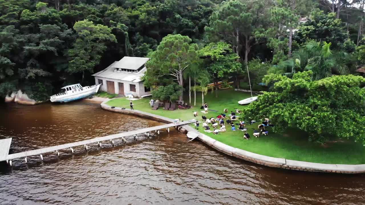 바다 앞 휴가 아파트 정원에서 야외에서 관광객 연습 요가 운동 그룹을 보여주는 공중 궤도 샷