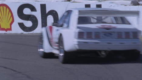 un auto de carreras blanco corre alrededor de una pista