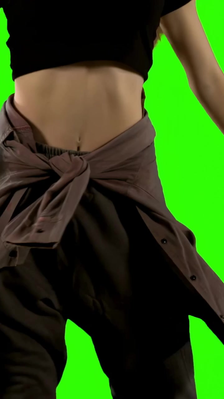 Video verticale: Telecamera che si sposta, donna che esegue torsioni del busto per una ripresa in chroma key con una maglietta annodata.