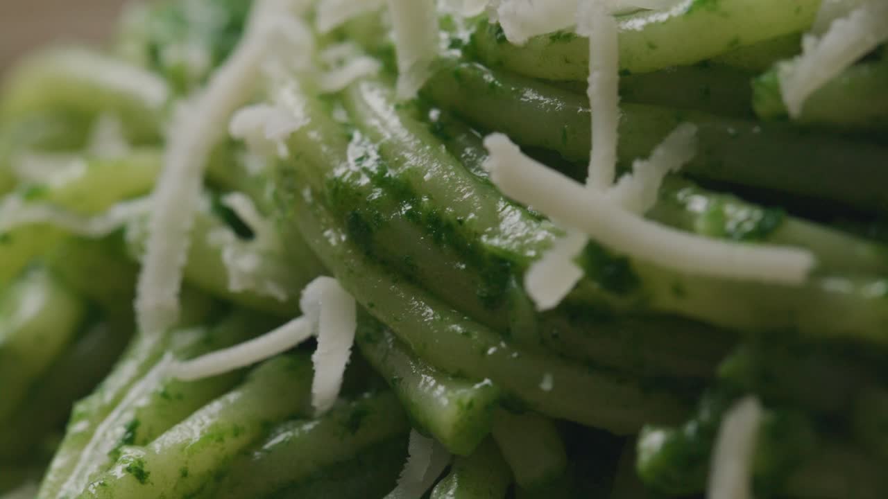 Grated Cheese Falling and Melting on Hot Spaghetti with Green Sauce