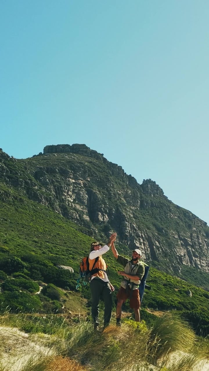 Due escursionisti che festeggiano con un cinque alto su un sentiero di montagna