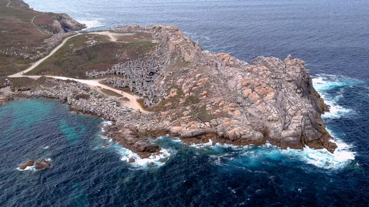 tomada aérea de un avión no tripulado de un camino estrecho sobre acantilados de papel, en morás, xove, lugo, galicia, españa rodeado de agua de mar azul durante el día
