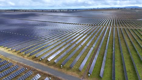 drone camera glides above an expansive solar panel installation in rural new south wales, australia, under daylight with partly cloudy skies and even lighting