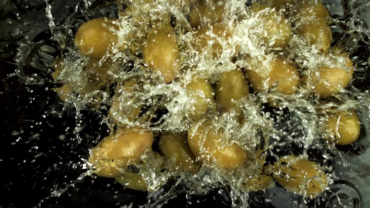 Olive verdi che cadono e schizzano nell'acqua al rallentatore.