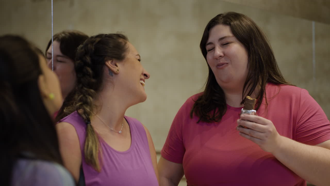 Women talking while one eats a snack
