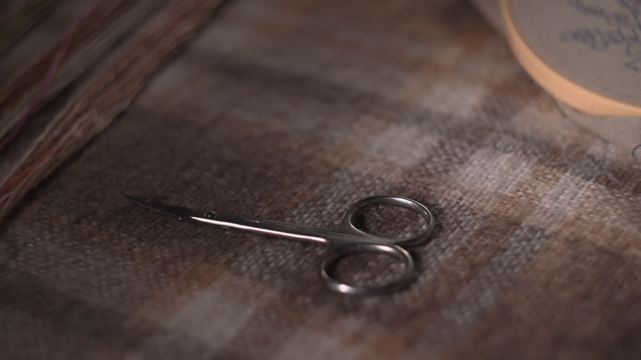 Primo piano della mano di una donna che posiziona un anello su tessuto scozzese, un delicato slow motion cattura morbidi e caldi riflessi sull'argento