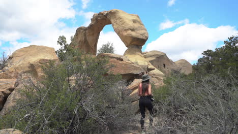 Rückseite-Der-Frau-Zu-Fuß-Auf-Dem-Wanderweg-Unter-Shiprock-Natural-Arch,-New-Mexico,-USA,-Vollbild-Zeitlupe