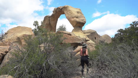 back of female walking on hiking trail under shiprock natural arch, new mexico, usa, full frame slow motion