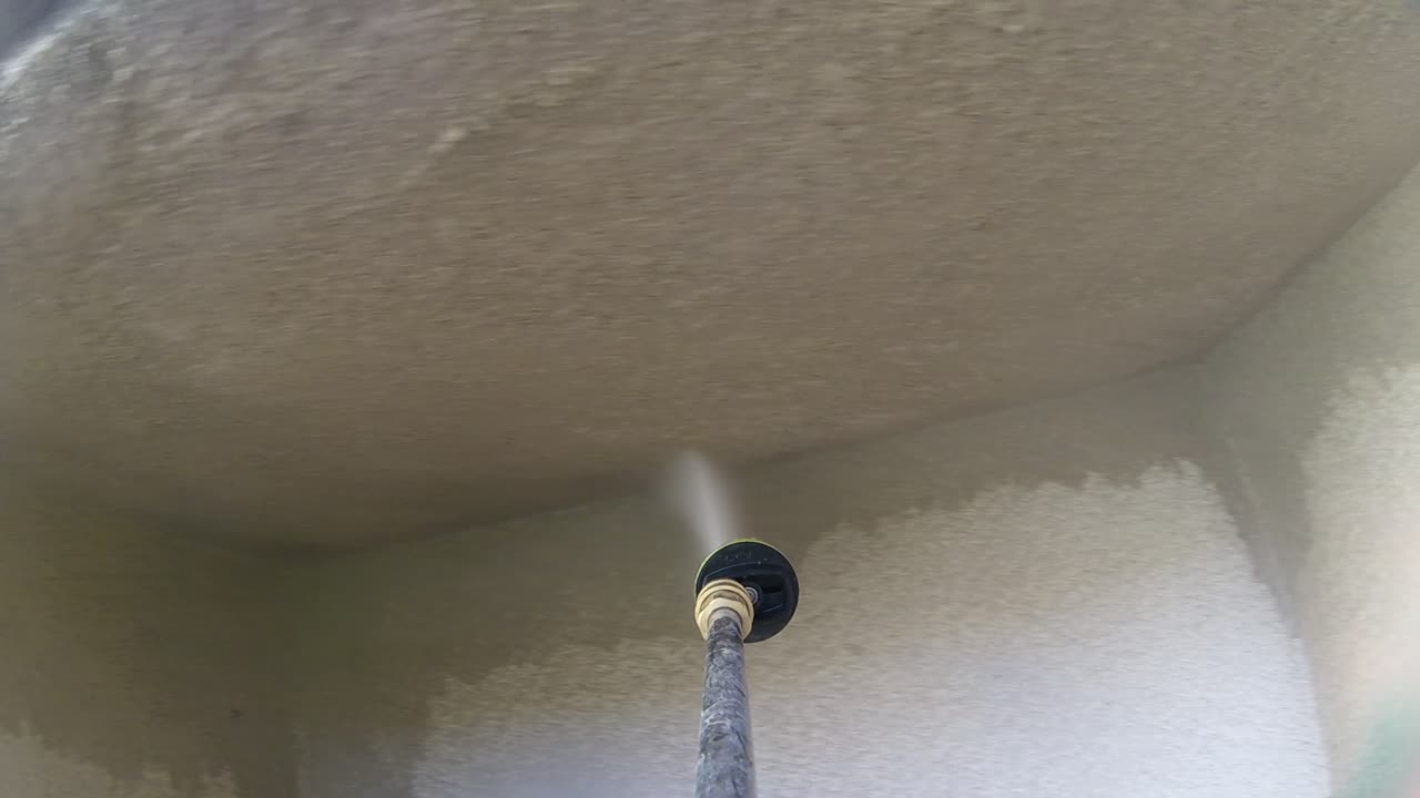 Ugello idropulitrice ad alta pressione che pulisce l'angolo di un muro di cemento, faccenda del fine settimana, POV