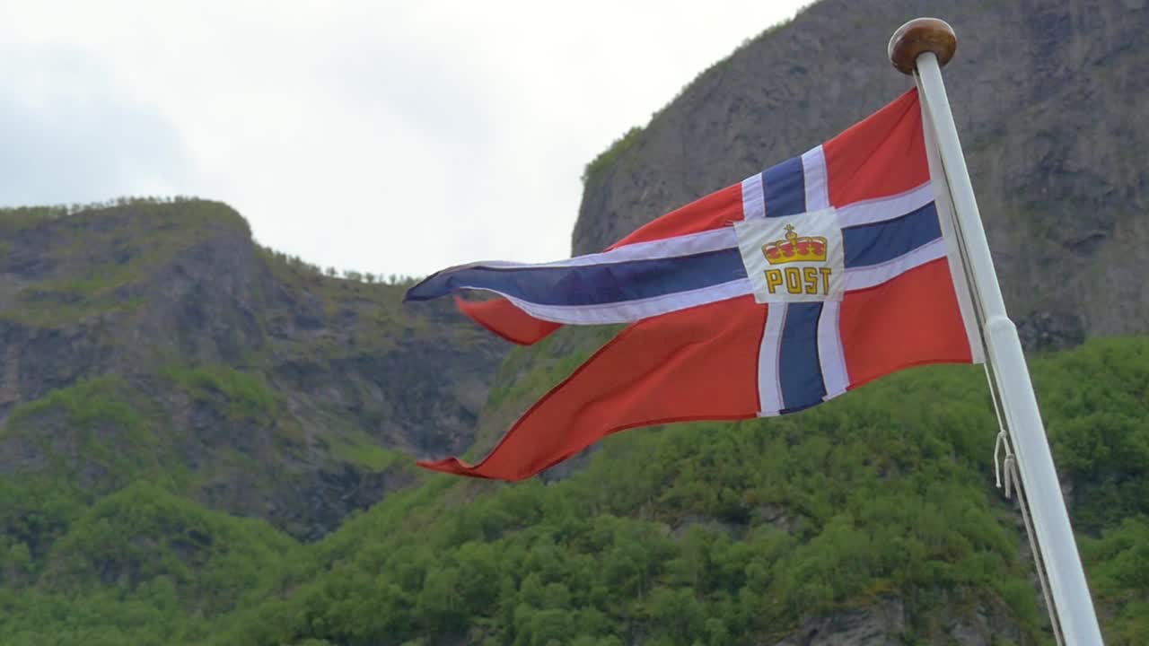 Slow motion shot of the Norwegian flag blowing in the wind on a fjord cruise.