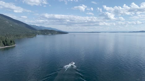 Lancha-Solitaria-En-Un-Pintoresco-Lago-Tranquilo-Durante-El-Verano-En-El-Lago-Flathead-En-Kalispell,-Montana---Vista-Aérea-De-Seguimiento-De-Drones