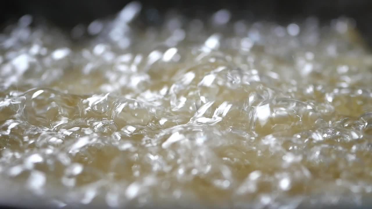 Primo piano di olio dorato in ebollizione e gorgogliante