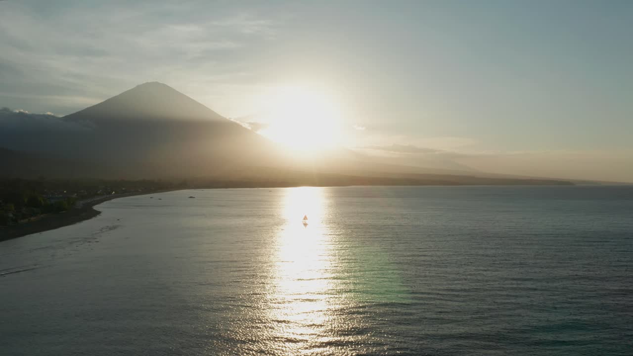 Tramonto luminoso con la silhouette del vulcano Monte Agung sulla spiaggia di Amed, Bali