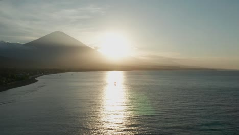 bright sunset with silhouette of volcano mount agung at amed beach, bali