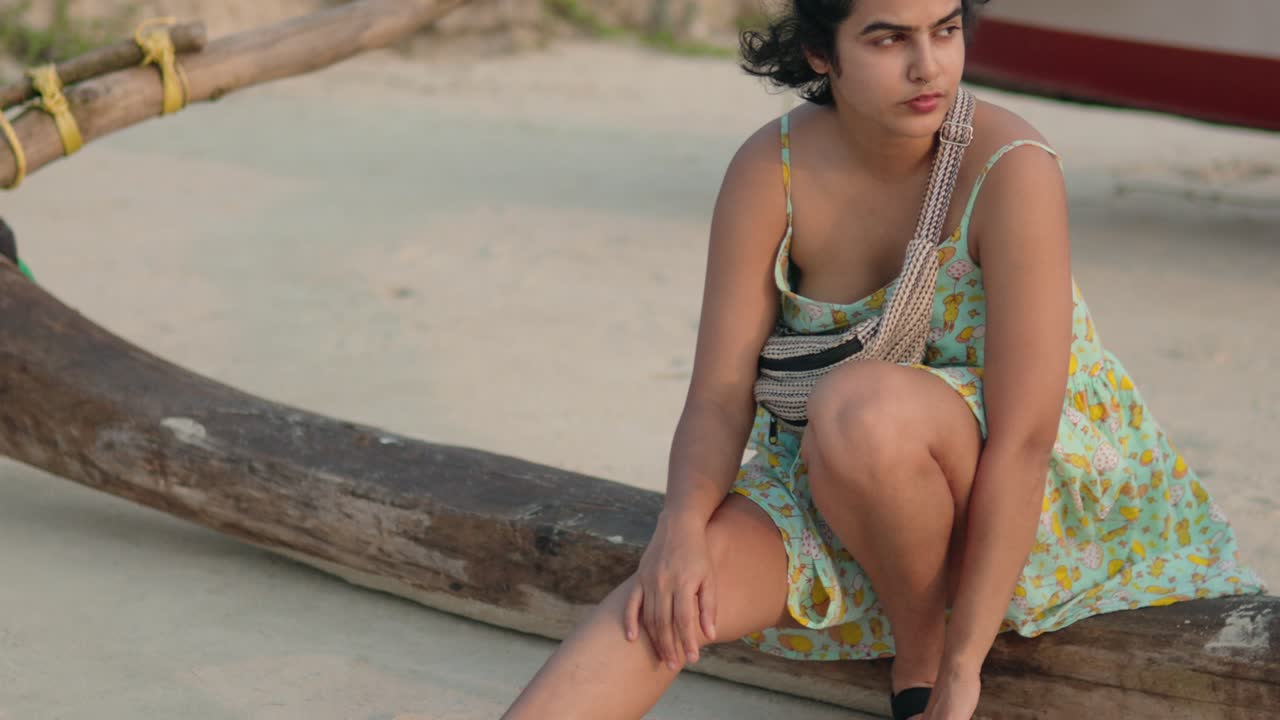 Una giovane donna indiana siede con grazia su una tradizionale barca da pesca in legno, finemente lavorata.