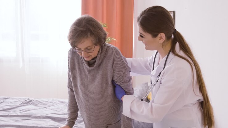 doctora ayuda a la anciana a levantarse de la cama