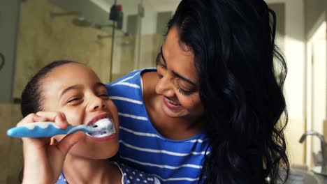 madre enseñando a su hija a cepillarse los dientes en el baño 4k