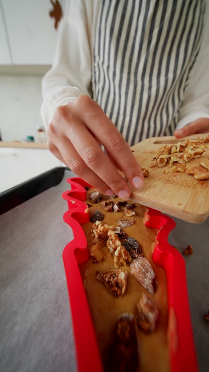 Close-up of Hands Adding Walnuts and Dried Figs to Cake Batter