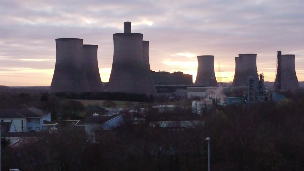 Fiddlers Ferry coal fired power station with sunrise behind landmark, Aerial view orbiting low above trees