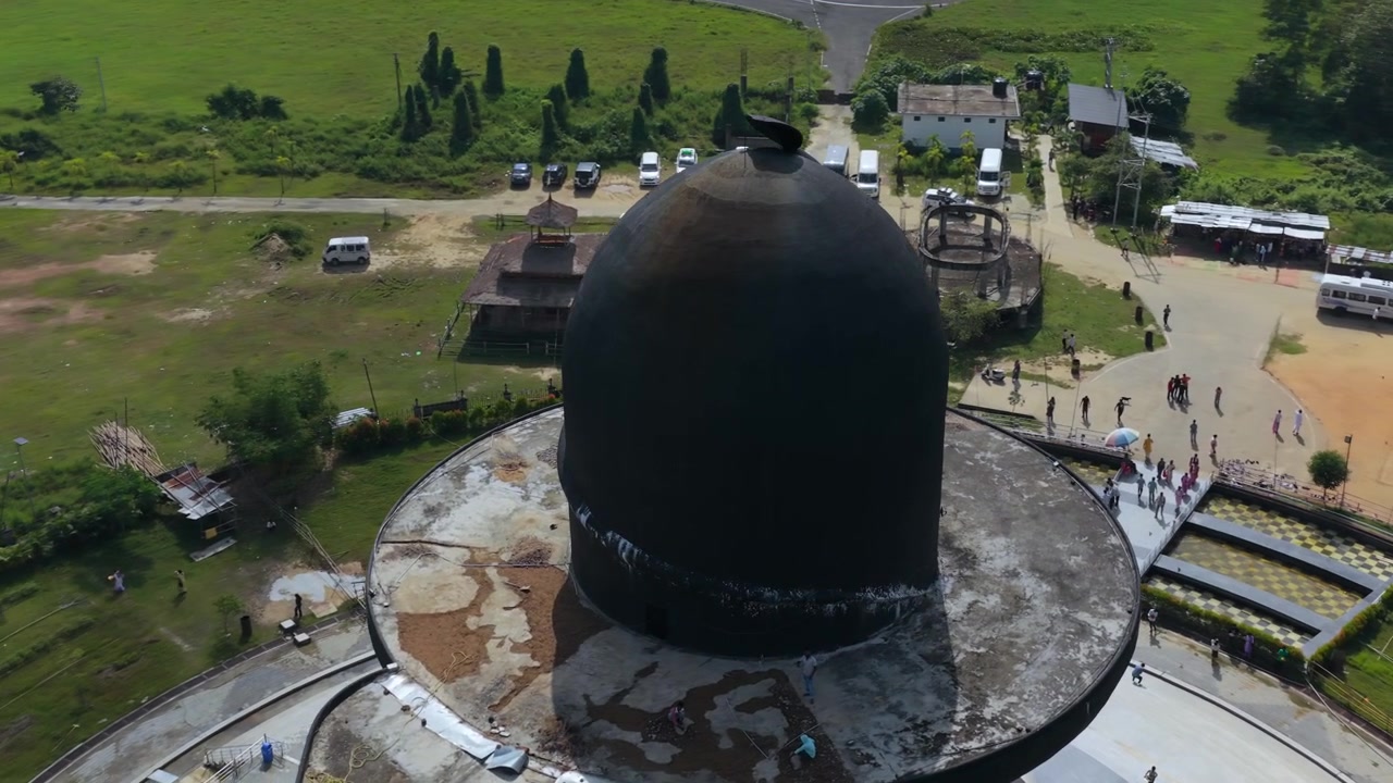 Cảnh quay drone điện ảnh về một bức tượng Shiva Lingam đen khổng lồ với những người hành hương đến thăm địa điểm linh thiêng ở vùng nông thôn Ấn Độ. Góc nhìn từ trên cao về kiến trúc tôn giáo Hindu