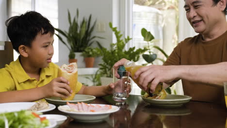 un hombre y un niño asiáticos sentados en la mesa.