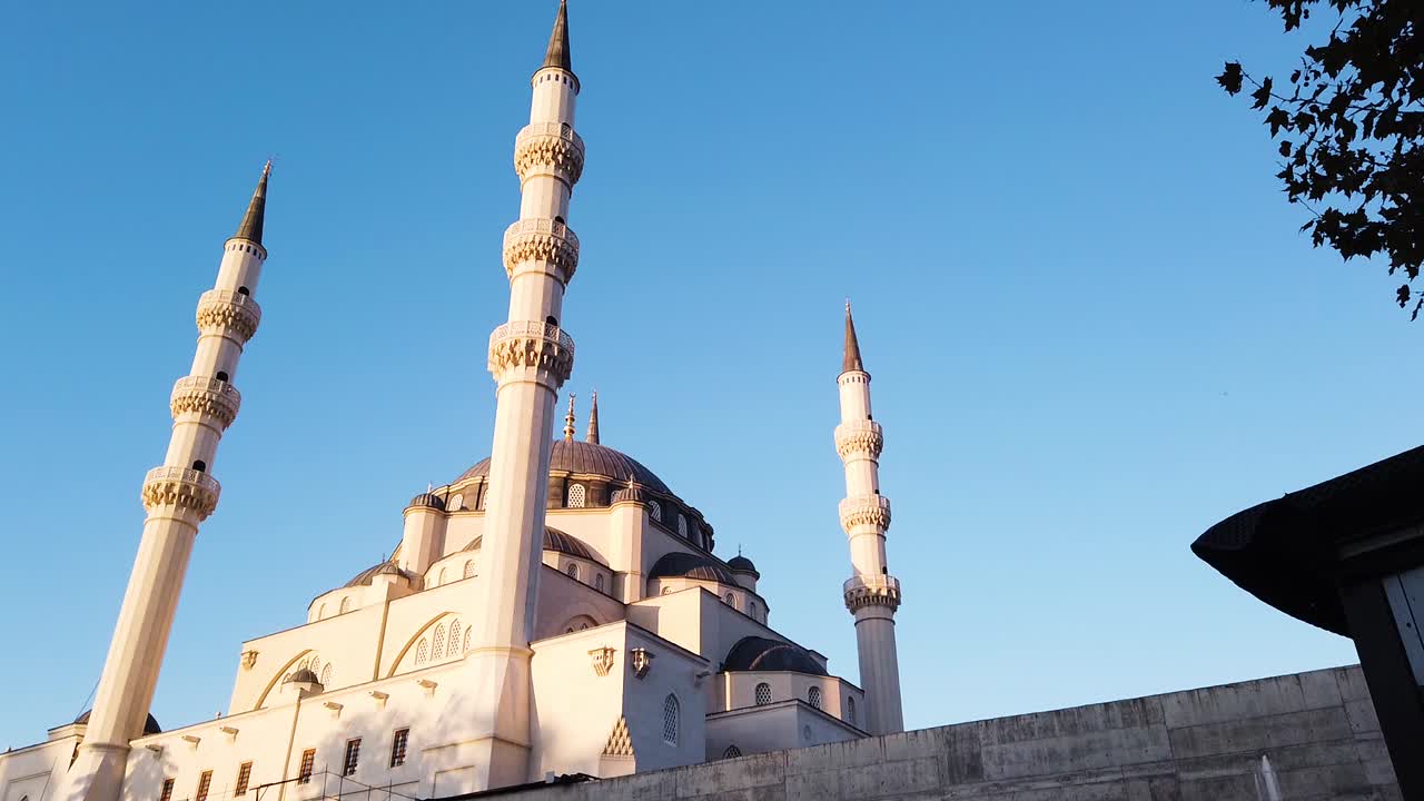 Panning shot of Namazgjah Mosque in Tirana with clear blue sky. Towers of mosque