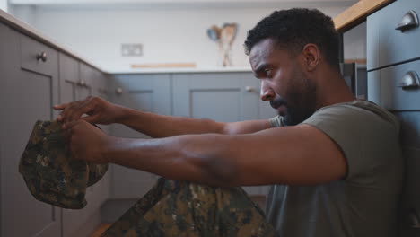 depressed american male soldier in uniform suffering with ptsd on kitchen floor on home leave