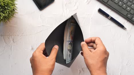Mano de persona poniendo dinero en efectivo en un sobre