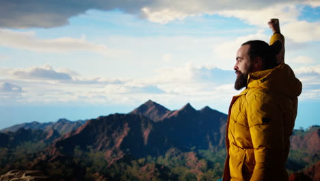 triumphant hiker stands at the mountain peak with his arms raised in victory