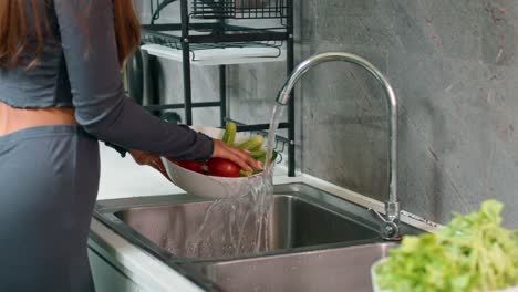 woman washing vegetables in a kitchen sink