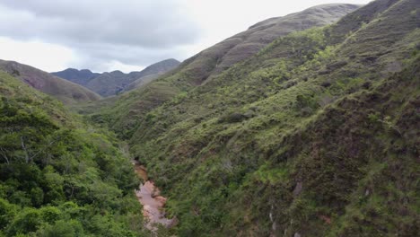 steep forested mountain slopes descend to remote narrow river valley