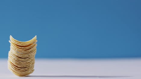 Close-up-view-of-stack-of-potato-chips-with-copy-space-against-blue-background