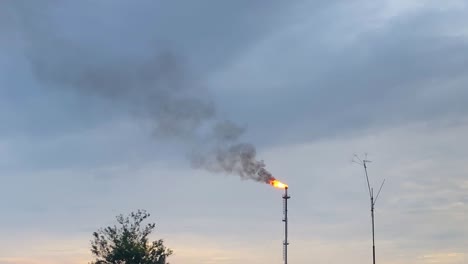 Fire-flaming-with-smoke-through-gas-pipe-at-a-gas-field-against-sky-at-the-evening-in-Bangladesh