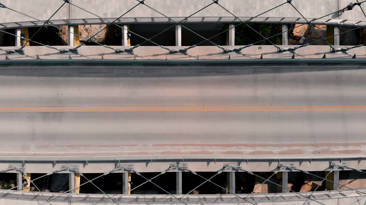Skateboarder weaving across bridge to commute downtown top down aerial