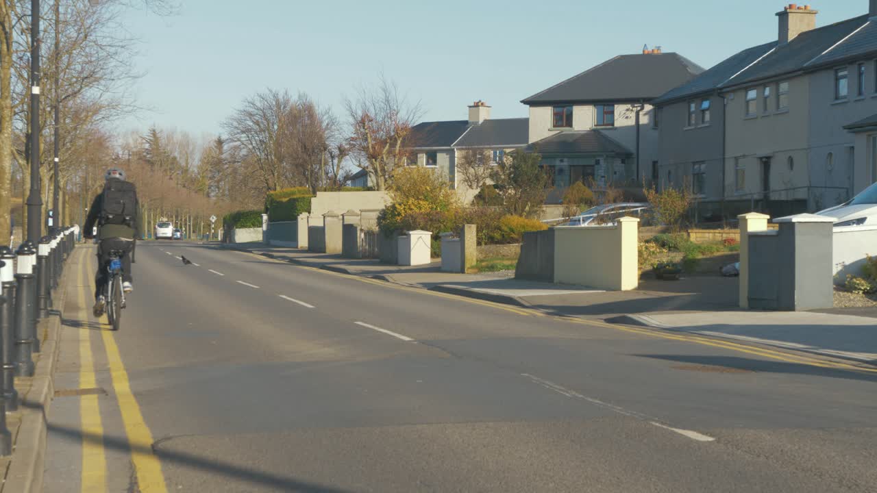 아일랜드의 조용한 마을 도로를 따라 자전거를 타고 먼 곳으로 향하는 남자