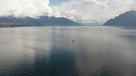 flying up to boat lying anchored on beautiful lake with mountains in the distance